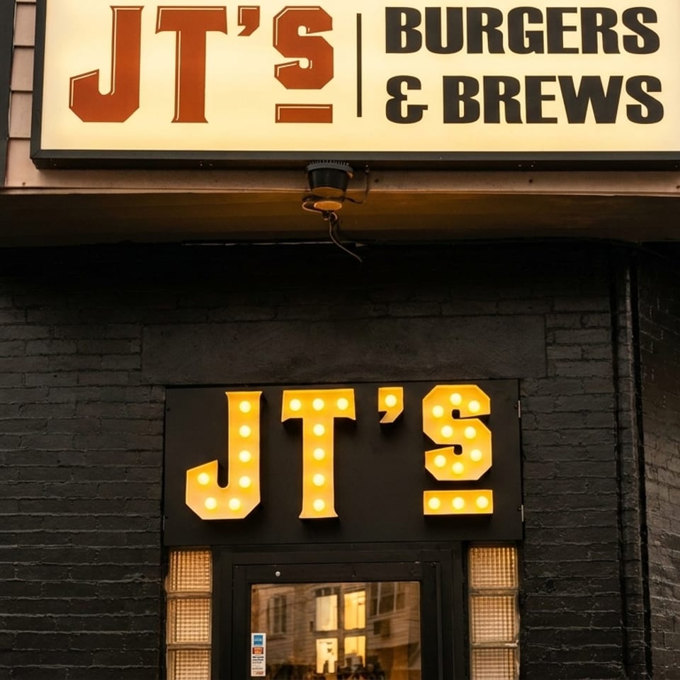 Exterior of JT's Burgers & Brews, featuring a large illuminated sign and a marquee entrance.